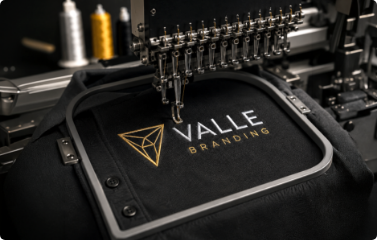 Valle Branding custom embroidery machine stitching a logo on black apparel
